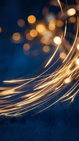 Golden light trails flowing across dark blue background with warm bokeh lights creating magical atmosphere for creative projects and presentations.