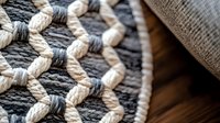 Detailed macro view of woven cotton rope pattern showing intricate knots and braided texture in black, white and gray colors on rustic fabric background.