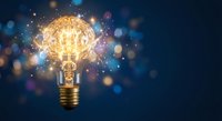 Light bulb with glowing brain filament surrounded by sparkling particles and bokeh lights on dark blue background representing creativity and innovation.