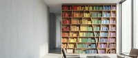 Modern home library interior with floor-to-ceiling wooden bookshelf filled with colorful books, ladder, natural lighting from large window, minimalist design.