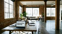 Modern loft coworking space with brick walls, wooden tables, laptops, and natural light, showcasing an innovative startup office environment.