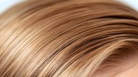 Close-up view of blonde wavy hair strands showing natural texture and highlights, creating soft flowing curves against neutral background. Professional hairstyling concept.