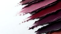 Burgundy and pink lipstick smears creating artistic texture on white background for cosmetic and beauty product advertising campaigns.
