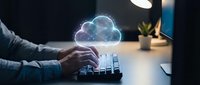 Professional typing on keyboard with glowing cloud computing hologram above, representing digital transformation and remote work technology solutions.