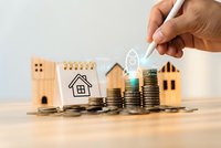 Hand drawing house icon above stacked coins with wooden house models representing real estate investment and property savings growth concept.