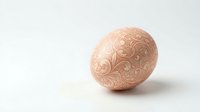 Elegant pink Easter egg with intricate golden floral patterns on white background, perfect for spring holiday decorations and greeting cards.