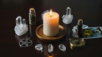Mystical altar setup with burning candle, crystals, pentagram, glass bottles and spiritual tools for witchcraft rituals and meditation practices.