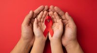 Adult and child hands protecting red awareness ribbon on red background symbolizing healthcare support and solidarity for medical causes.