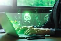 Businessman working on laptop with green holographic environmental sustainability icons including CO2 reduction and renewable energy symbols.