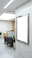 Modern office lobby with blank white poster frame on marble wall for advertising mockup and corporate branding display in contemporary business interior.