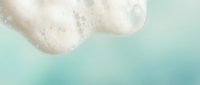 Soft fluffy white clouds floating in pastel mint green sky creating dreamy atmospheric background for wellness and meditation content.