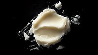 Creamy white shea butter or cosmetic balm on black background, raw organic ingredient for natural skincare and beauty products.