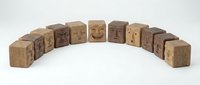 Wooden blocks with carved emotional faces arranged in semicircle showing range of human expressions from sad to happy on white background.