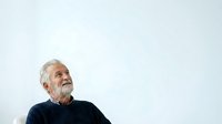 Senior man with gray hair and beard, wearing dark navy sweater, looking upward thoughtfully against white background. Suitable for healthcare, wellness, aging, retirement, and lifestyle editorial use.
