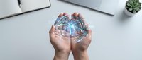 Hands holding holographic globe with network connections above modern workspace. Digital transformation and global connectivity concept for business presentations.