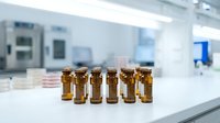 Amber glass vials arranged on laboratory bench in modern pharmaceutical research facility with sterile equipment background.