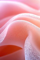 Soft pink fabric with delicate glitter texture creates gentle waves and folds, capturing light and shadow in an ethereal macro composition. Suitable for romantic designs.