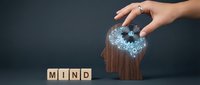 Wooden blocks spelling mind with hand pouring glowing digital particles from head silhouette, representing thoughts, creativity, and mental processes for business and psychology concepts.