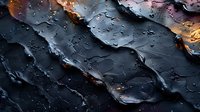 Dramatic macro shot of dark wet surface with water drops and golden light reflections creating abstract pattern with deep shadows and highlights.