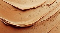 Smooth creamy foundation texture with gentle swatches showing cosmetic product consistency. Luxury makeup background in warm nude beige tones.