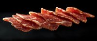 Thinly sliced cured meat arranged diagonally on dark background showing texture and marbling of premium charcuterie for food photography and menu design.