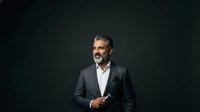 Mature male professional with salt-and-pepper beard wearing dark blazer and white shirt against black background, suitable for corporate portraits, business websites, and professional headshots.