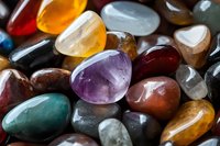 Collection of polished gemstones and healing crystals in various colors including amethyst, agate, jasper and quartz for jewelry making and spiritual practices.