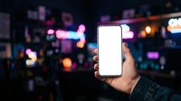 Hand holding smartphone with blank white screen against vibrant neon city lights at night. Use for app mockups, mobile technology marketing, urban digital communication concepts.