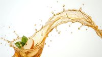 Golden liquid splash with fresh green mint leaf creating dynamic wave motion against clean white background for beverage advertising and culinary design.
