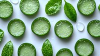 Fresh sliced cucumber circles and whole mini cucumbers arranged in pattern on white background, top view. Natural organic food photography.