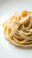 Creamy pasta carbonara with black pepper and cheese on white background, ready for food and restaurant design use.