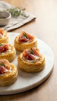 Elegant puff pastry appetizers topped with prosciutto and fresh rosemary on white plate, gourmet party food for entertaining and special occasions.