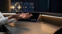 Team of diverse professionals stacking hands together over desk with glowing digital hologram interface, symbolizing unity, collaboration, and commitment to shared business goals and success.