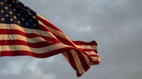 Waving flag against dramatic cloudy sky symbolizing patriotism, freedom and national pride for Memorial Day, Independence Day celebrations.