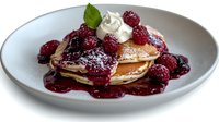 Stack of fluffy pancakes topped with fresh raspberries, whipped cream and berry sauce on gray ceramic plate, served for breakfast or brunch against white background.