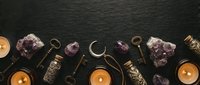 Mystical flat lay with amethyst crystals, vintage brass keys, burning candles and dried herbs on dark wooden background for spiritual practices.