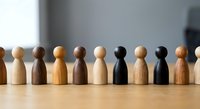 Diverse wooden figurines in row representing teamwork, inclusion and unity concepts for business presentations and diversity training materials.