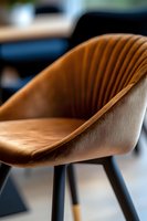 Modern brown leather dining chair with ribbed backrest detail and black metal legs, showcasing contemporary furniture design in soft focus macro shot.