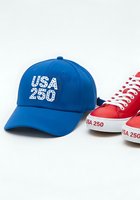 Blue baseball cap with USA 250 embroidered text and red canvas sneakers with white laces, isolated on white background for merchandise and apparel design use.