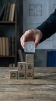 Businessman hand placing wooden cube with shield icon on pyramid of blocks with security symbols representing data protection and cybersecurity strategy.