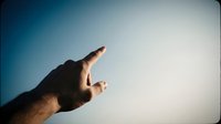 Hand reaching toward bright sky with finger pointing upward against gradient blue to white background suggesting hope and aspiration for success.