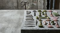 Ancient ceramic pottery collection with bowls, vessels and tools displayed on stone surface for archaeological museum exhibition or historical research.