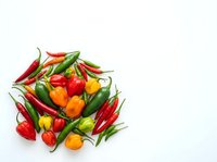 Fresh red, green, and yellow hot chili peppers arranged on white background, isolated produce for culinary, cooking, and food design projects.
