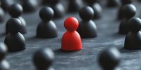 Standing out from crowd concept shown through red figure among black figures, leadership and individuality business metaphor on dark background.