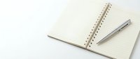Open spiral notebook with blank pages and silver pen on white background for office work and note taking.