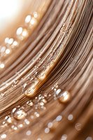Macro view of water droplets on golden brown hair strands creating bokeh effect with warm sunlight illumination.