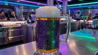 Futuristic beer mug with circuit board pattern in neon-lit cyberpunk bar setting with purple and green lighting effects.