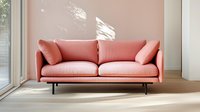 Modern coral pink sofa with metal legs against pastel wall in sunlit minimalist living room interior with natural light and shadow play on wall.