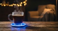 Steaming hot coffee in clear glass mug on blue saucer sits on wooden table with warm bokeh lights and cozy living room background for cafe concepts.
