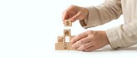 Business professional stacking wooden blocks with icons representing growth strategy and development concepts on white background.